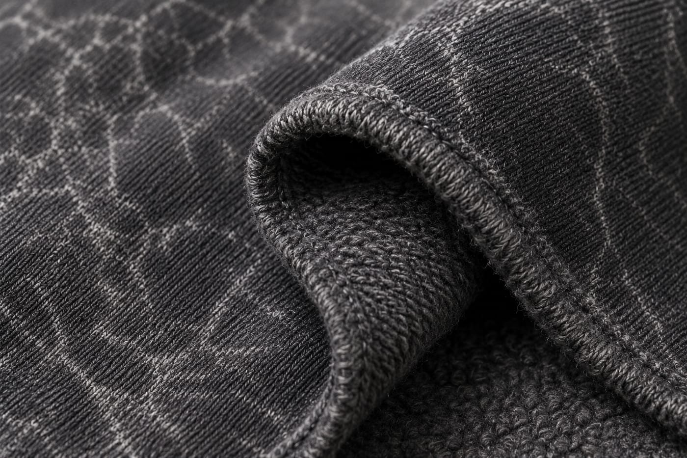 Close-up of a folded hem on 400 GSM acid wash French terry, showing the looped back and mineral wash marbling