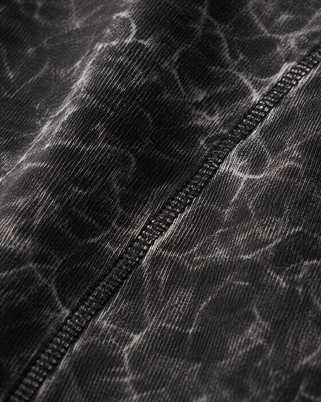 Close-up of the shoulder seam on a 240 GSM acid wash tee, showing the mineral wash marbling across the cotton jersey