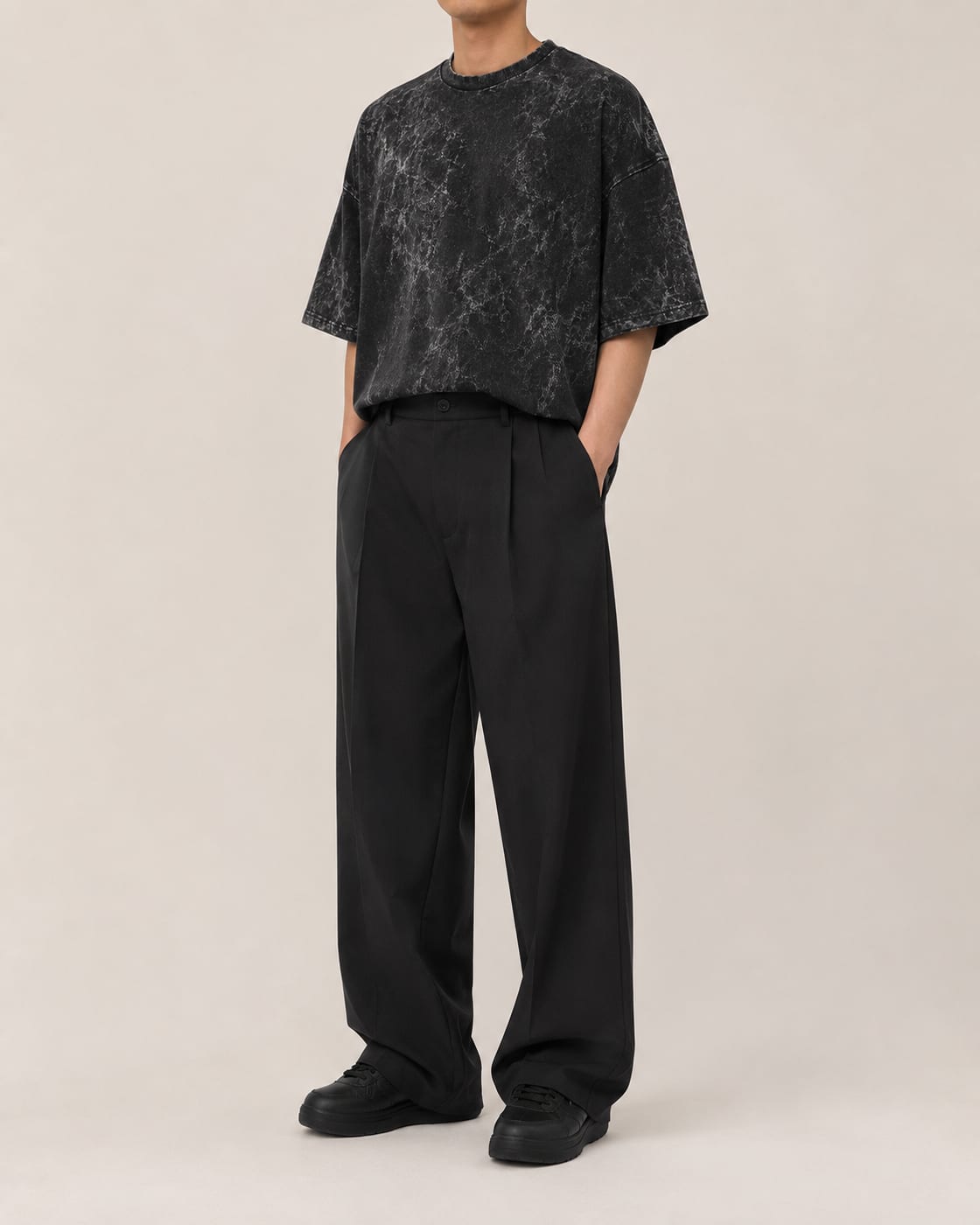 Model wearing a charcoal 240 GSM oversized acid wash tee with black wide-leg trousers