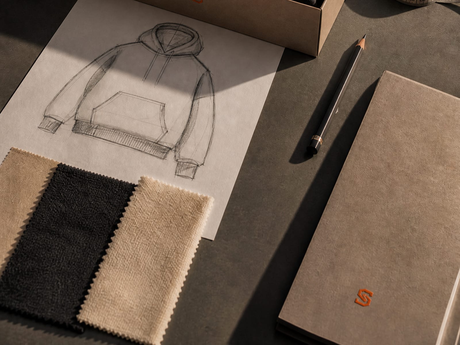Apparel design sketches, fabric swatches and tech pack on studio workspace